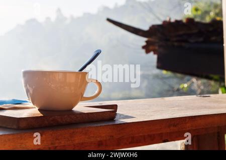 Coffee cup and napkin on wooden table in morning light Stock Photo
