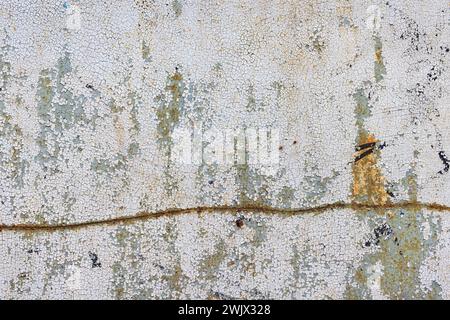 Peeling and cracked paint on an old metal sheet with a crooked rusty line drawn through it. Stock Photo