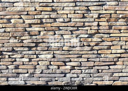 A wall of large river stone pebbles illuminated by sunlight. Stock Photo