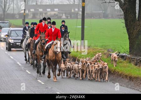Chewton Mendip, Somerset, UK.  17th February 2024.  UK Weather.  Riders and hounds of the Mendip Farmers Hunt head for home along the B3135 Roemead Road after a trail fox hunt near Chewton Mendip in Somerset on a warm misty day.   Picture Credit: Graham Hunt/Alamy Live News Stock Photo