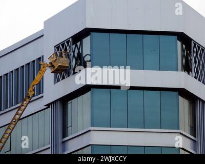 Cairo, Egypt, January 25 2024: Painting service and maintenance of the exterior of a building, the worker is on a hydraulic bucket boom lift vehicle, Stock Photo