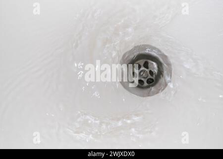 Swirl of water flows down the drain in the bathroom Stock Photo