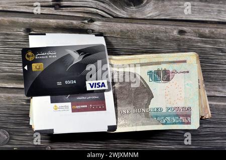 Cairo, Egypt, February 12 2024: Stack of Egyptian money banknotes of 100 Hundred pounds and Banque Misr or Egypt Bank electronic payment VISA card for Stock Photo