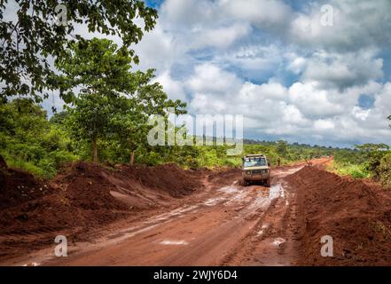 A 4-wheel drive vehicle drives down a wet and muddy red earth road near Msanga in rural Tanzania. Stock Photo