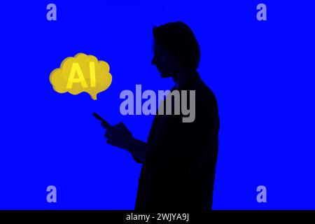 Silhouette of an elegant businessman using AI in a modern smartphone on social media, standing on a blue glowing background, a futuristic AI concept Stock Photo