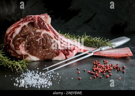 Wagyu tomahawk steak on a slate background with salt, pepper, garlic and peppers Stock Photo