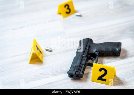 Augsburg, Bavaria, Germany - February 16, 2024: Symbolic image crime scene after a shooting spree staged scene. Pistol with shell casings scattered on the ground with police evidence markings *** Symbolbild Tatort nach einer Schießerrei gestellte Szene. Pistole mit Patronenhüsel auf dem Boden verteilt mit Beweismittel Markierungen der Polzei Stock Photo