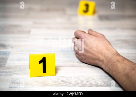 Augsburg, Bavaria, Germany - February 16, 2024: Symbolic image of corpse found posed scene. The arm of a dead man in an apartment next to police evidence markings *** Symbolbild Leichenfund gestellte Szene. Der Arm von einem toten Mann in einer Wohnung neben Beweismittel Markierungen der Polizei Stock Photo