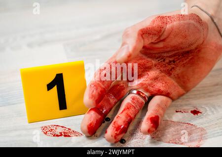 Augsburg, Bavaria, Germany - February 16, 2024: Symbolic image crime scene of a murder case staged scene. Man smeared with blood lying on the ground with police evidence markings *** Symbolbild Tatort eines Mordfalls gestellte Szene. Mit Blut verschmierter Mann liegt auf dem Boden mit Beweismittel Markierungen der Polizei Stock Photo