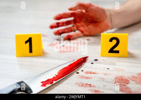 Augsburg, Bavaria, Germany - February 16, 2024: Symbolic image crime scene of a murder case staged scene. Man smeared with blood lying on the ground with police evidence markings *** Symbolbild Tatort eines Mordfalls gestellte Szene. Mit Blut verschmierter Mann liegt auf dem Boden mit Beweismittel Markierungen der Polizei Stock Photo