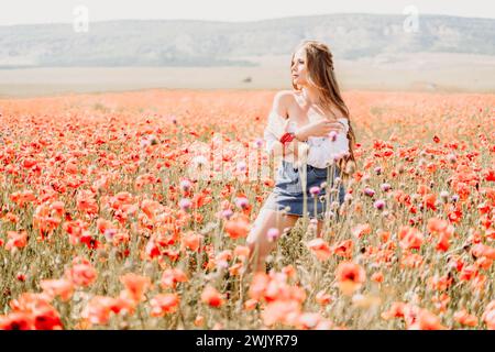 Woman poppies field. Side view of a happy woman with long hair in a poppy field and enjoying the beauty of nature in a warm summer day. Stock Photo