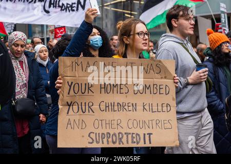 Leeds, UK. 17 FEB, 2024. A pro palestinian protestor holds a sign that reads 'imagine it was your homes bombed, your children killed, and other countries supported it' as they marched through Leeds city center. Credit Milo Chandler/Alamy Live News Stock Photo