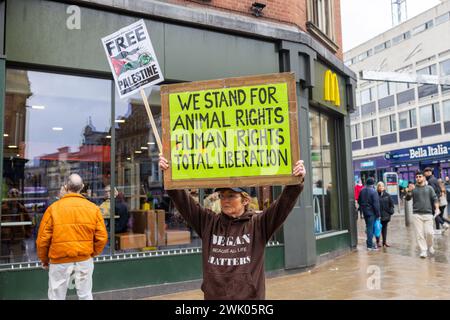 Leeds, UK. 17 FEB, 2024. A women protests outside Mcdonalds with a placard that reads 'We stand for Animal Rights, Human Rights, Total liberation' Credit Milo Chandler/Alamy Live News Stock Photo