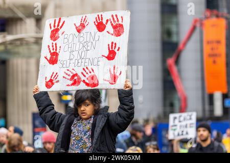 Leeds, UK. 17 FEB, 2024. A young child at the pro palestine protest in Leeds city square holds a sign with bloodied handprints and reads 'Bombing Children is not self-defence' . Credit Milo Chandler/Alamy Live News Stock Photo