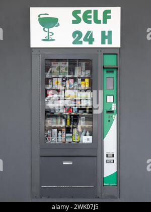 Italy - February 17, 2024: Self 24-hour vending machine for pharmaceuticals and condoms on gray wall and with green logo sign Stock Photo
