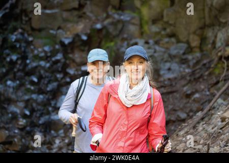 active good looking attractive vibrant happy senior middle aged couple hiking in the woods and exercising and smiling and enjoying life. Stock Photo
