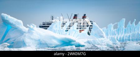 Fish Islands, Antarctica - January 12, 2024: Cruise ship Seabourn Pursuit hidden behind beautiful iceberg in Antarctica. Stock Photo