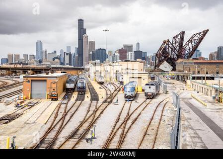 Diesel locomotives at a suburban train depot on a cloudy day. Downtown Chicago Skyline and an open draw bridge are in background Stock Photo