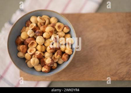A Top view of bowl of hazelnuts on wood board with a napkin in the background Stock Photo