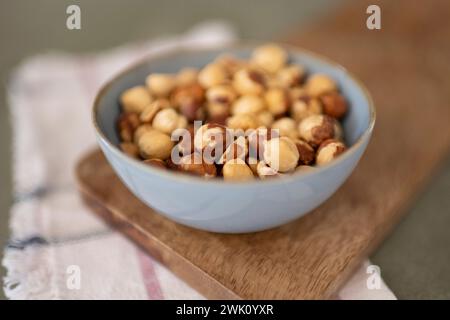A Side view of bowl of hazelnuts on wood board with a napkin in the background Stock Photo