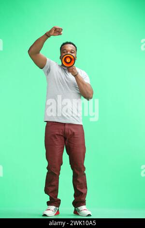 Man, full-length, on a green background, with a megaphone Stock Photo