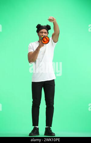 A man, full-length, on a green background, with a megaphone Stock Photo