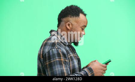 Man, close-up, on a green background, using a phone Stock Photo