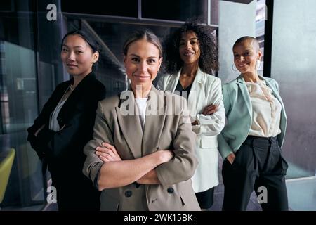 Group diverse attractive female professional in suits with arms crossed looking smiling at camera. Stock Photo