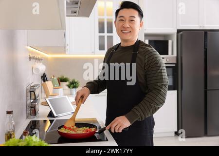 Happy man cooking dish on cooktop in kitchen Stock Photo