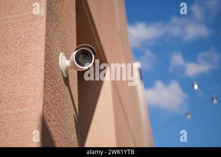 CCTV security camera operating on building against blue sky  Stock Photo