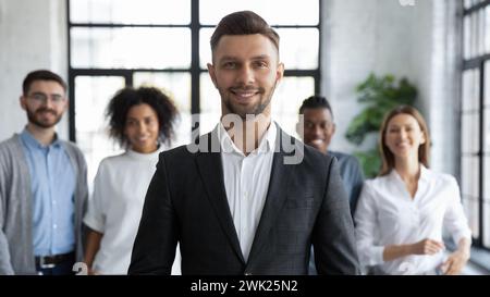 Happy young leader with team of supportive employees in background Stock Photo