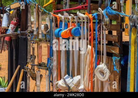 street vendor hardware shop on the side of the road with various goods, belts, jack, fire extinguisher, wood pallets, pick axe mirrors. in bright vivi Stock Photo