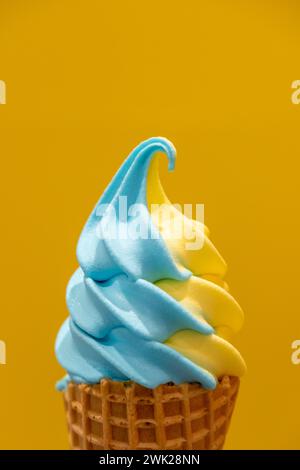 Blue and Yellow ice cream in a waffle cone, with yellow background Stock Photo