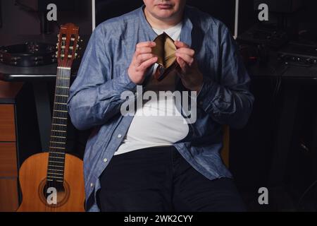 A musician in a recording studio holds an empty wallet in his hands. The workplace of a sound engineer in a recording studio Stock Photo