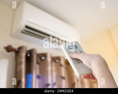 Hand hold remote control directed on the air conditioner Stock Photo