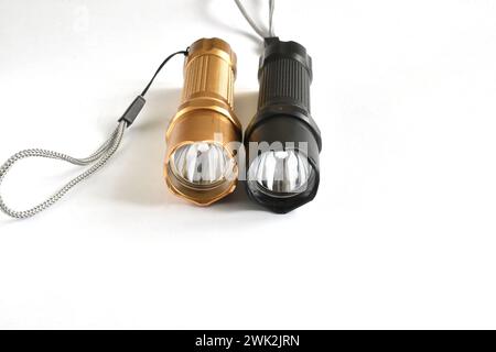 Two hand-held flashlights of the same design, but of different colors lie on a white background. Stock Photo