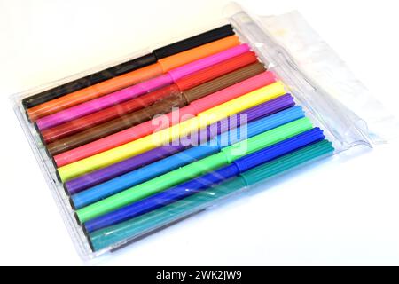 Markers of different colors in transparent packaging lie on a white background. Stock Photo