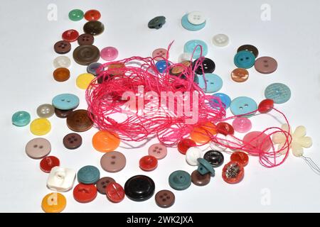 The background pattern was created with multi-colored buttons and thin red thread scattered on the table. Stock Photo