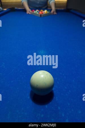 Player racking the balls. Eight-ball pool game at six pocket blue table Stock Photo