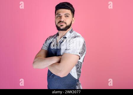 Brunette worker, handyman with beard posing indoors, standing with crossed hands. Stock Photo