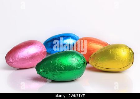 Five brightly colored chocolate Easter eggs on white. Stock Photo