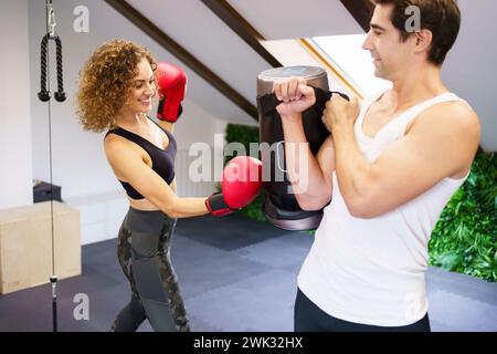 Trainer helping sportswoman during boxing training Stock Photo