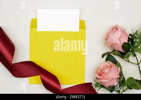 Blank greeting card, flyer or invitation card mockup with pink roses, red ribbon on grunge background Stock Photo