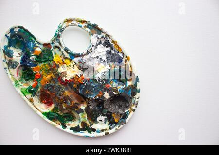 Palette with bright colours on white background. Abstract art. Paint palette with copy space. Drawing hobby. Mix of various colours. Stock Photo
