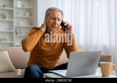 Stressed elderly businessman have phone conversation, working from home Stock Photo