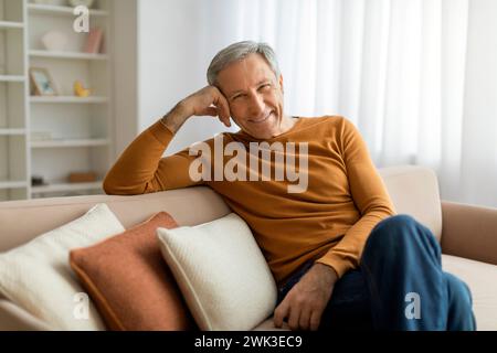 Relaxed handsome grey-haired senior man chilling on couch Stock Photo