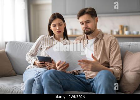Spouses reviewing documents and using tablet at home Stock Photo