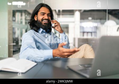 Indian Guy Talking On Cellphone Working On Computer At Office Stock Photo