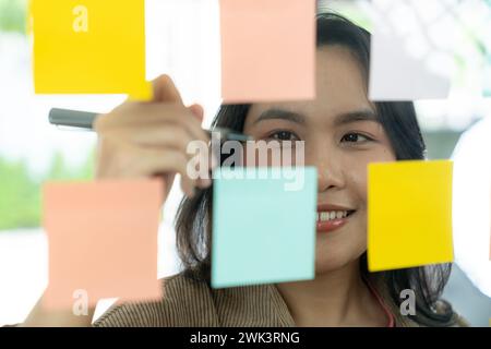 Successful businesswoman writing business plan on adhesive notes in the office. Stock Photo