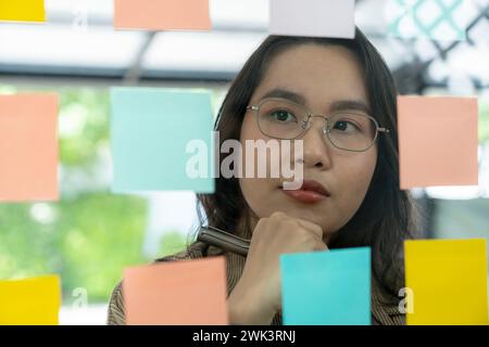 Successful businesswoman writing business plan on adhesive notes in the office. Stock Photo
